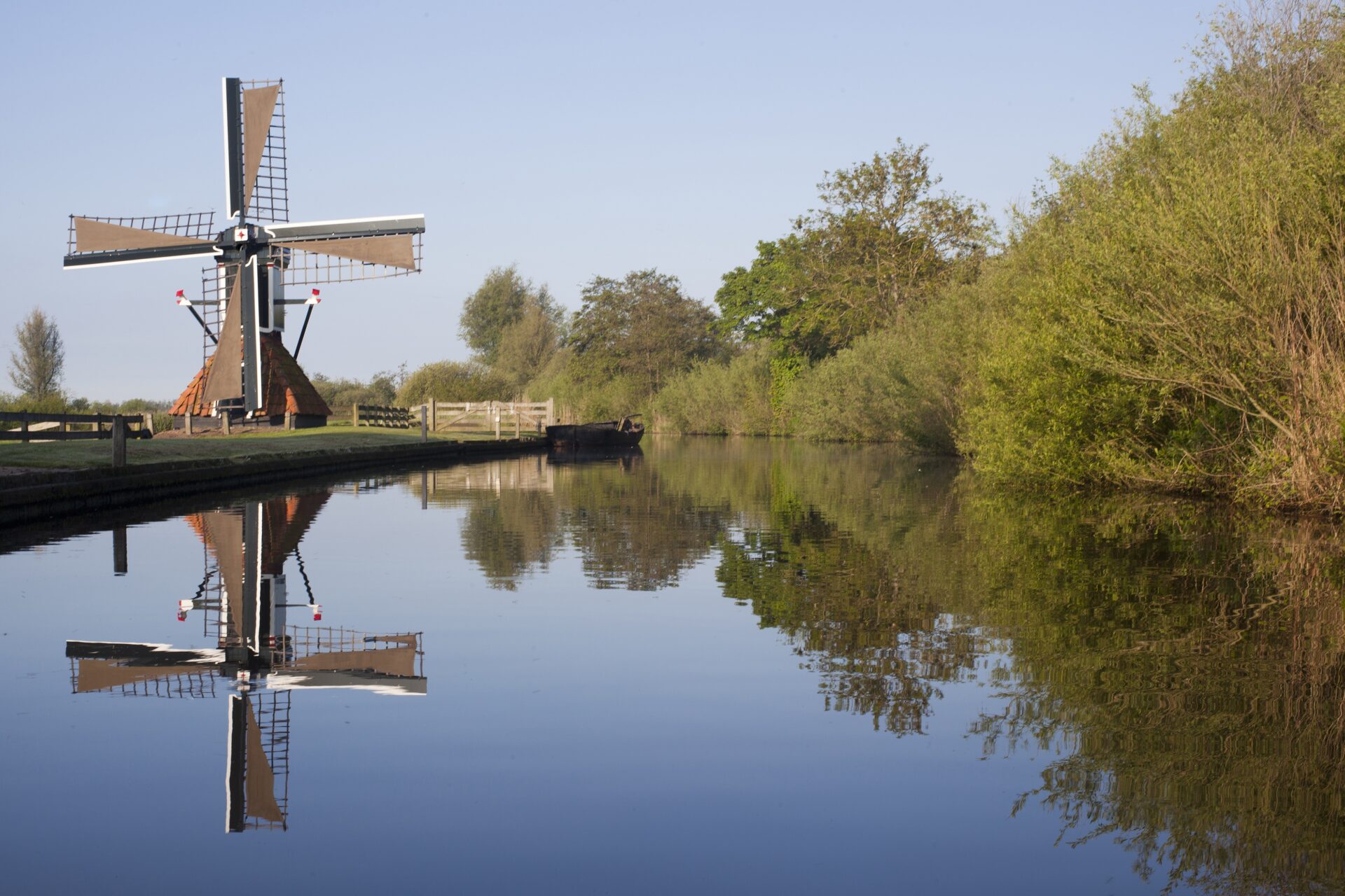 Een ouderwetse hollandse molen langs het water in Friesland