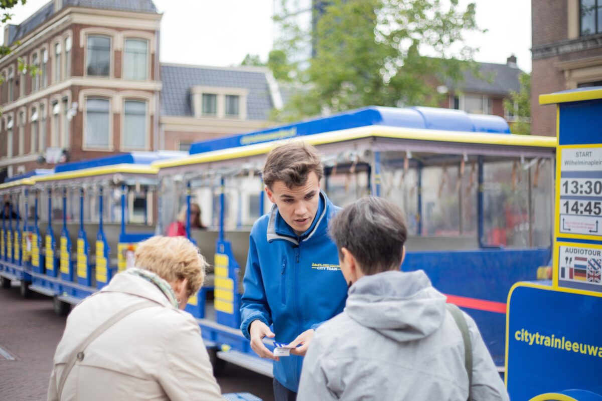 Vrolijke interactie tussen de tourguide van de Citytrain en twee bezoekers