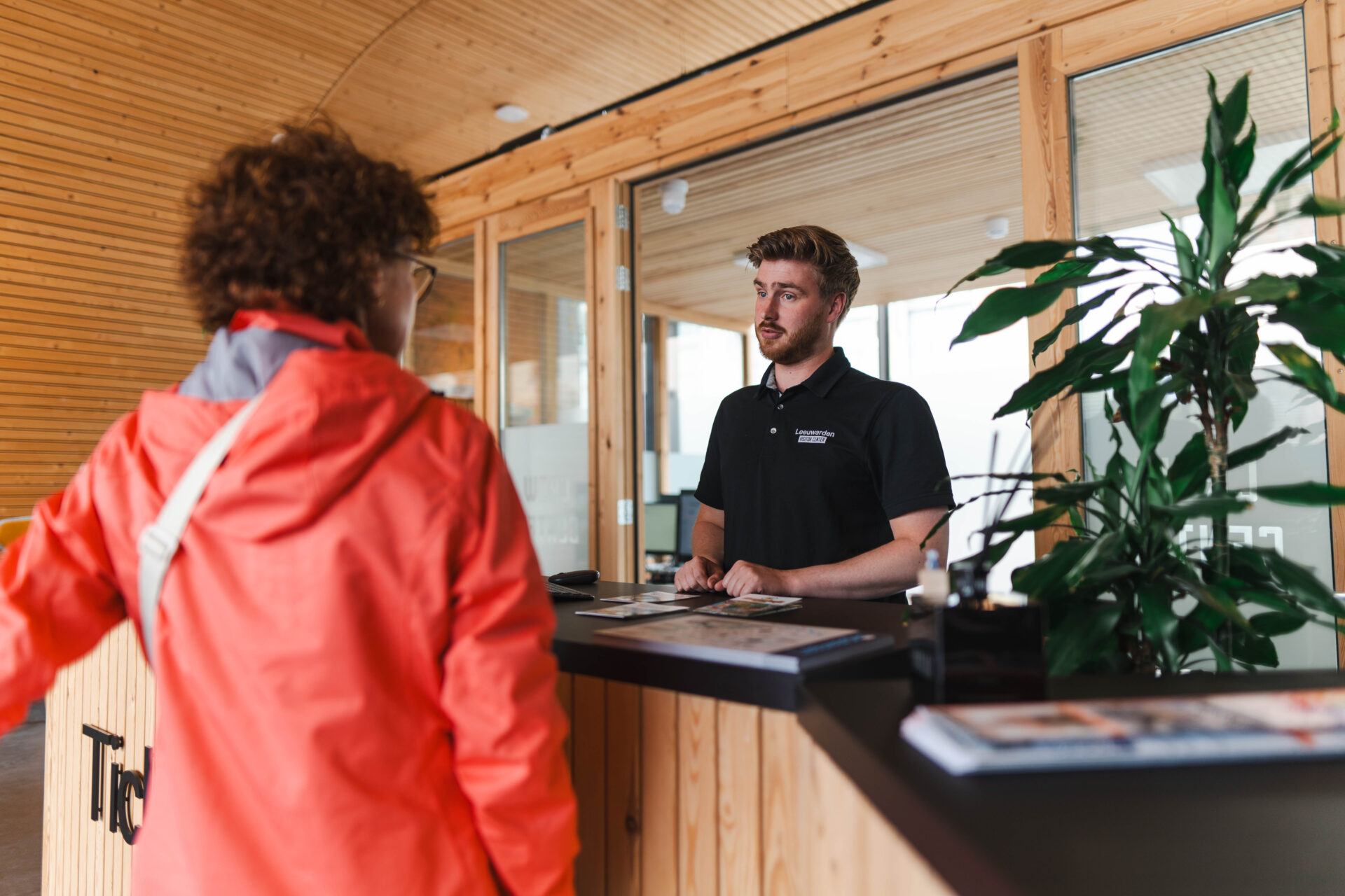 Medewerker van het Visitor Center Leeuwarden helpt een bezoeker op weg in de stad