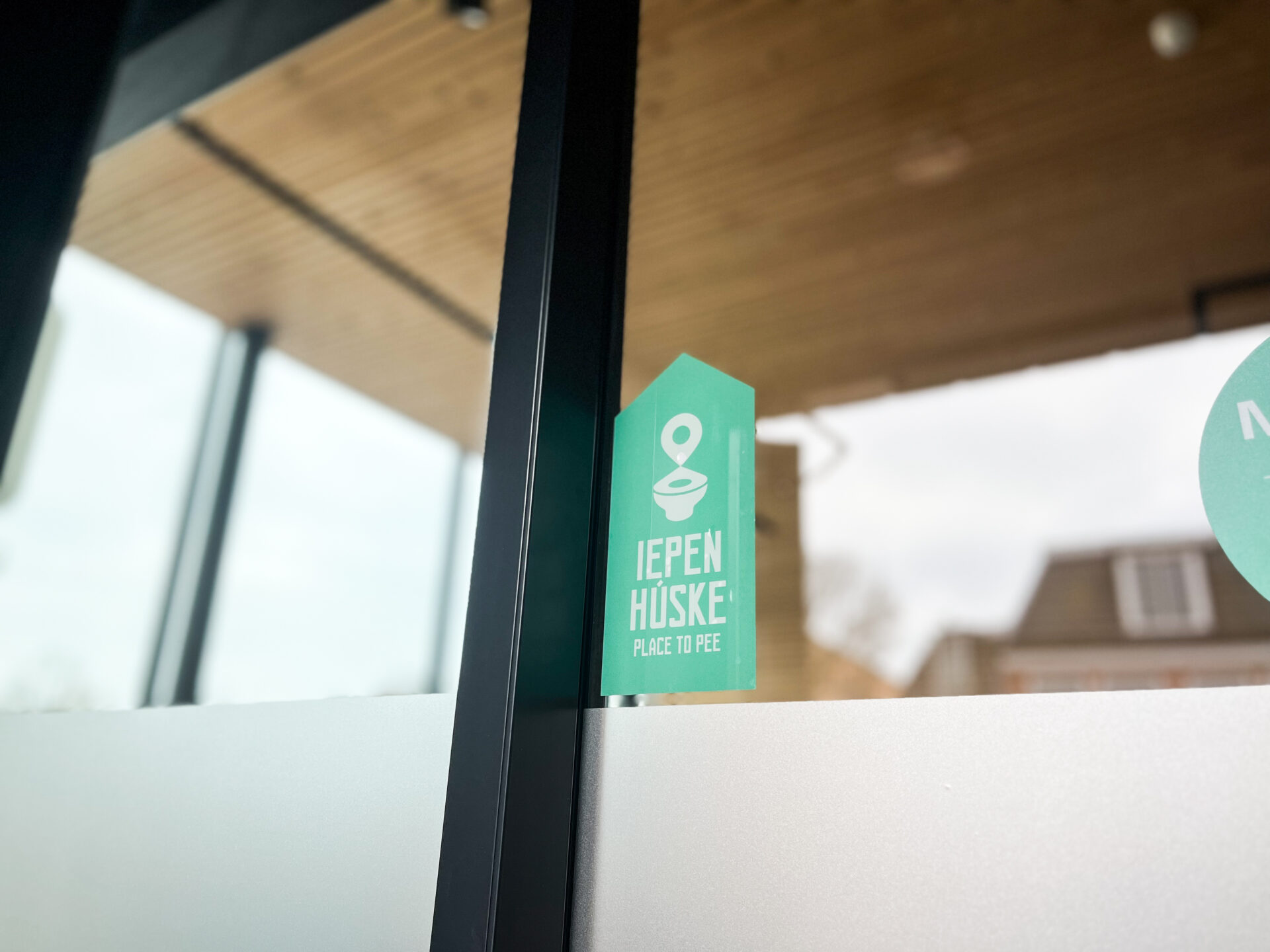Iepen Húske place to pee sticker op raam deur waar mensen naar het toilet kunnen
