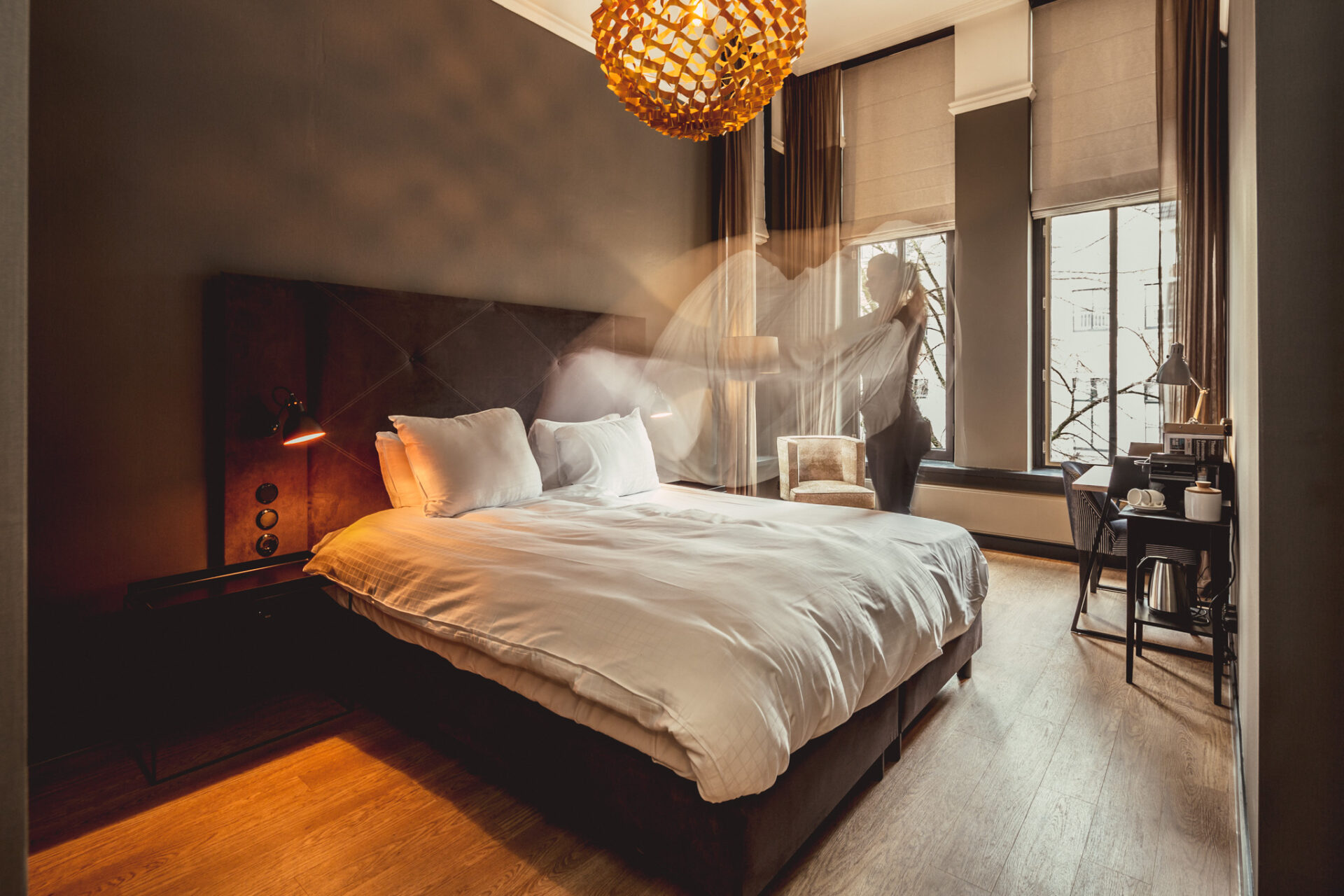 Post-Plaza oud postkantoor slaapkamer hotelkamer met een groot bed en een vrouw, medewerker die het bed op maakt