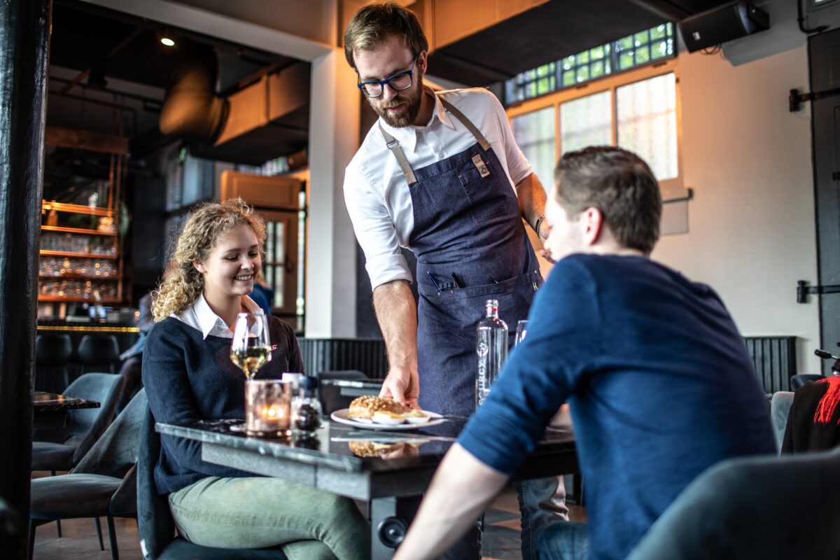 Een ober serveert het eten bij een jong stel