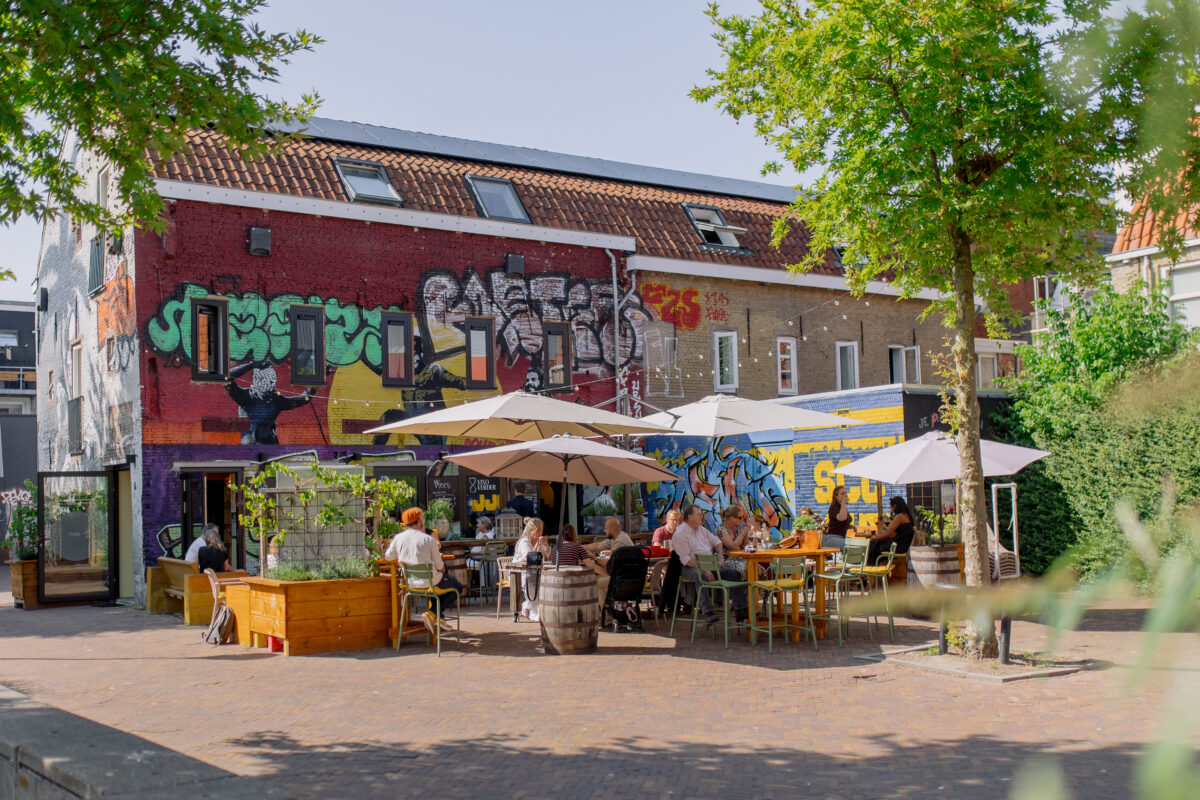 Het zonovergoten terras van wijnbar Vino & Verder op het verstopte plekje in de Haniasteeg. Het terras heeft een urban vibe door alle graffiti en street-art.