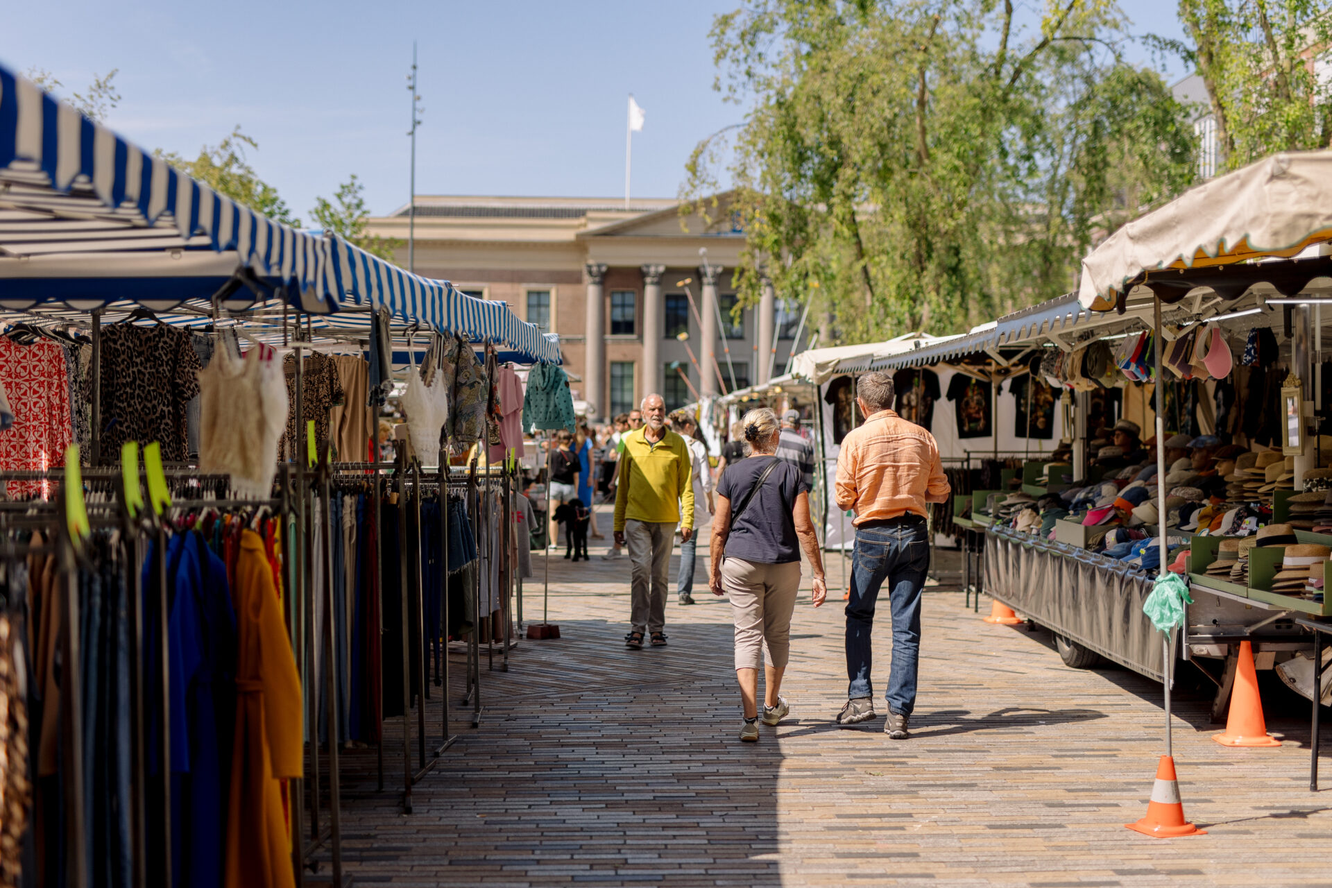 Winkelende mensen op de vrijdagmarkt op het Wilhelminaplein met op de achtergrond het gerechtsgebouw.