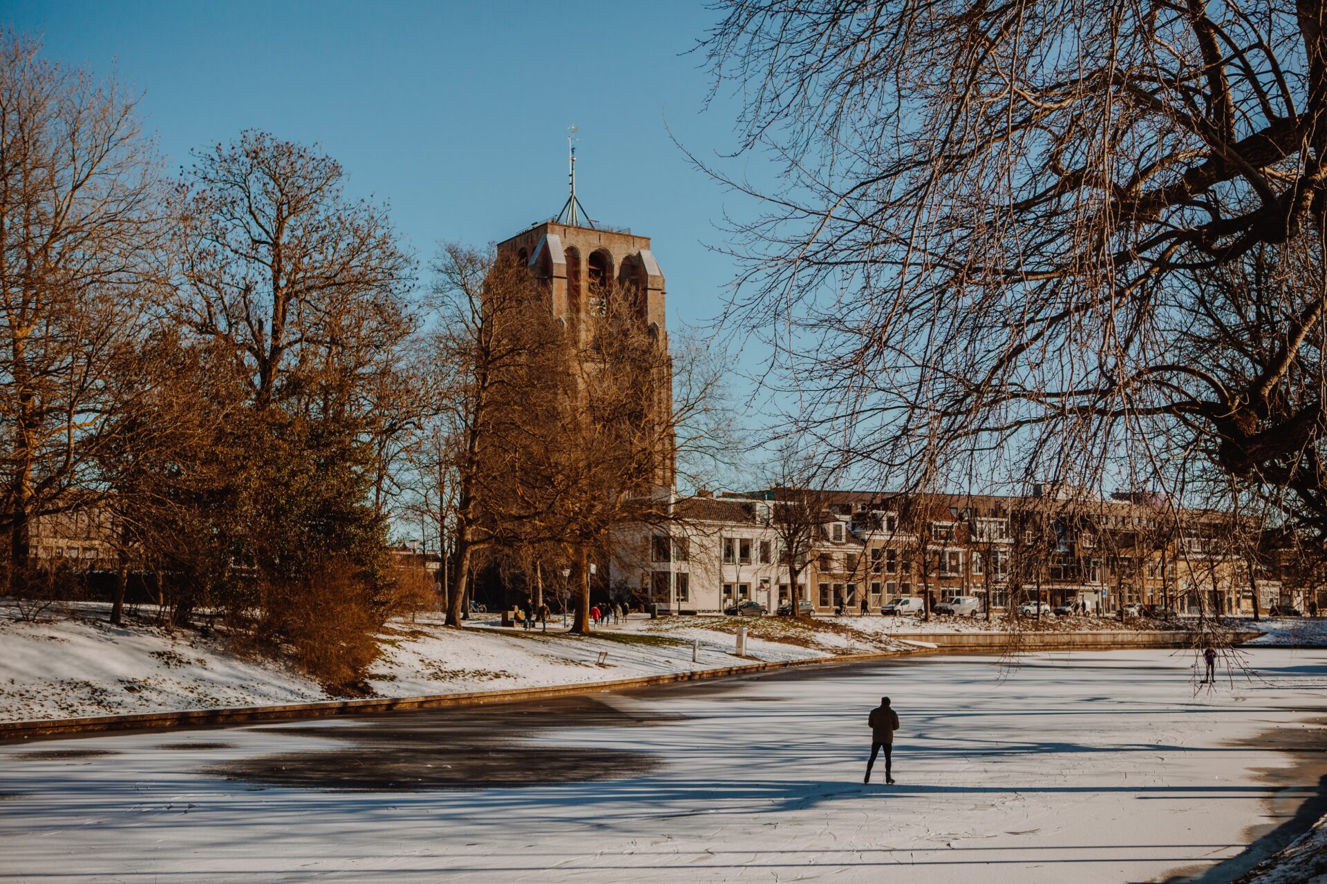 Mensen schaatsen door de Prinsentuin in Leeuwarden met de Oldehove op de achtergrond