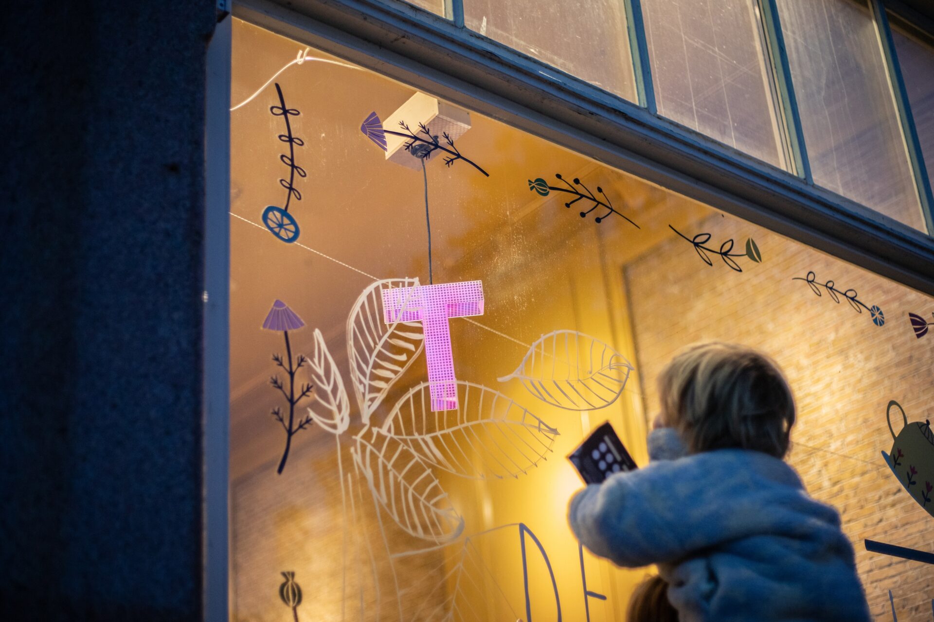 Een peuter op de nek van zn vader kijkt naar een etalage tijdens een speurtocht