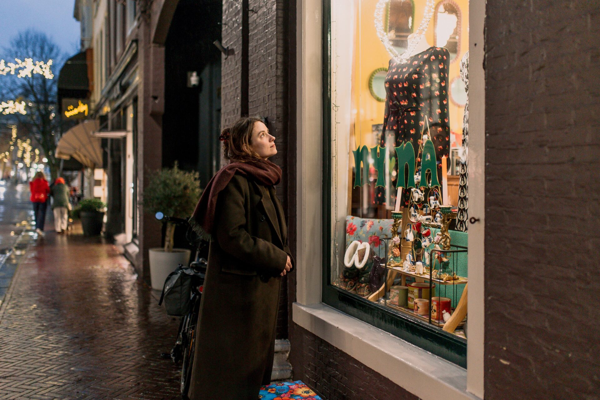 Een vrouw kijkt naar een versierde etalage in de wintermaanden in Leeuwarden