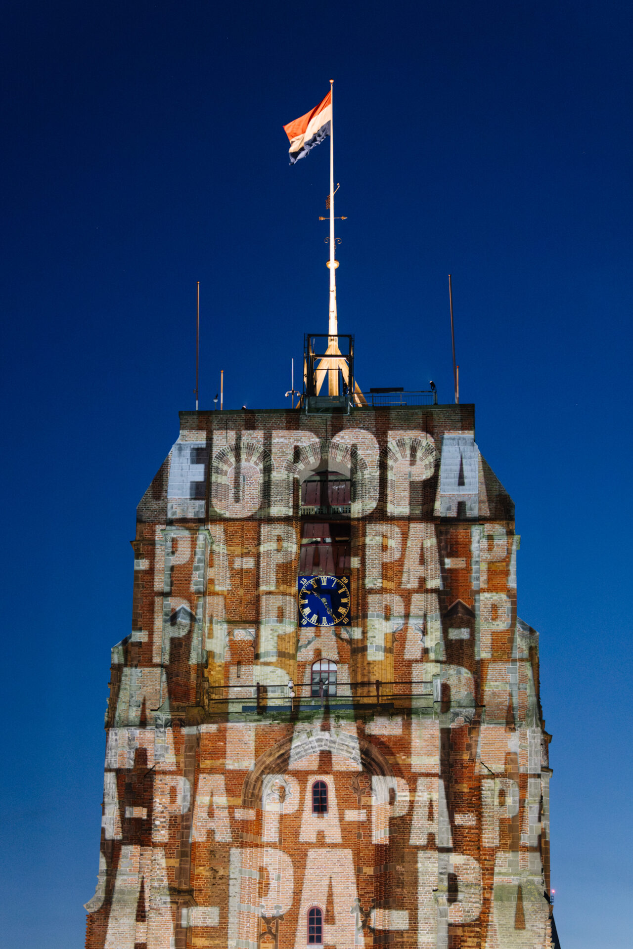 Een verlichtte Oldehove met de tekst van Joost Europapa van een muziekfeest op het oldehoofsterkerkhof in Leeuwarden