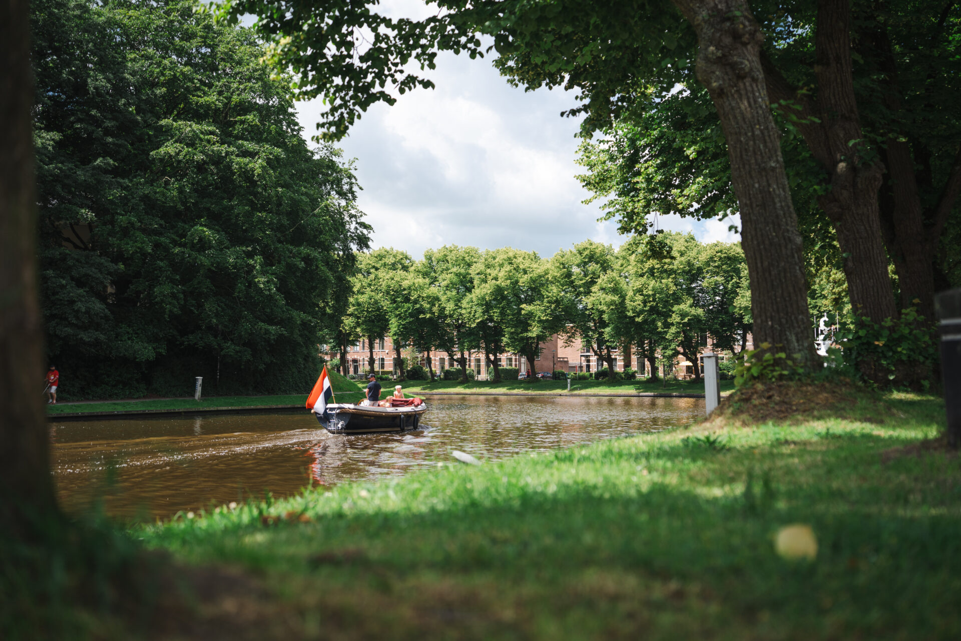 Een groene Prinsentuin. Er vaart een sloep.