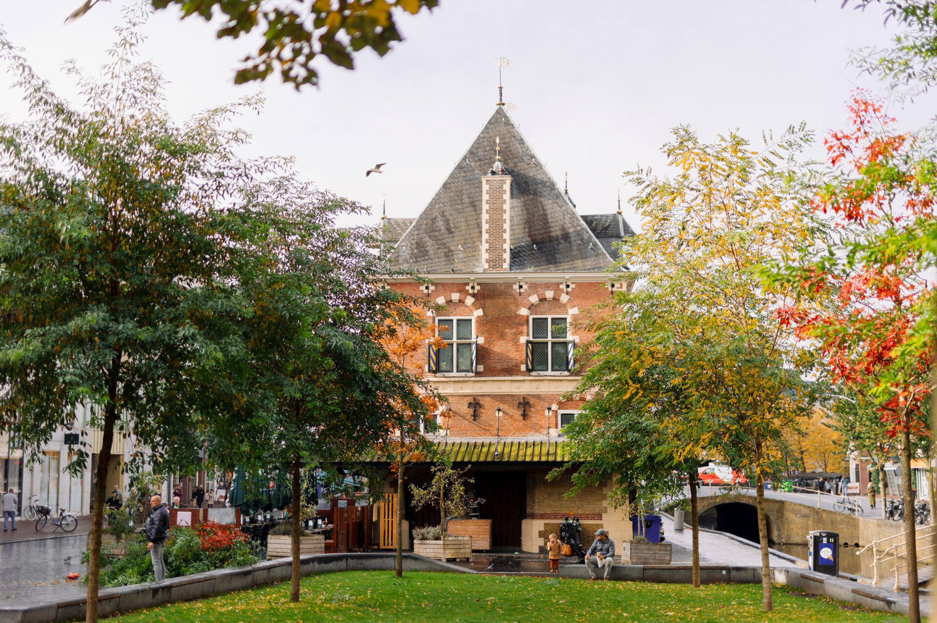 De Waag die omringt is met herfstbomen in rood, oranje, groen, geel.