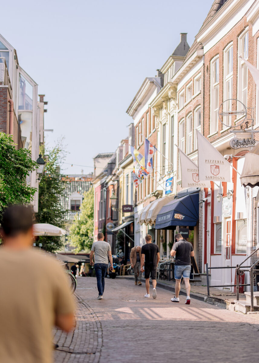 Mensen wandelen tussen de historische panden in de Grote Hoogstraat.