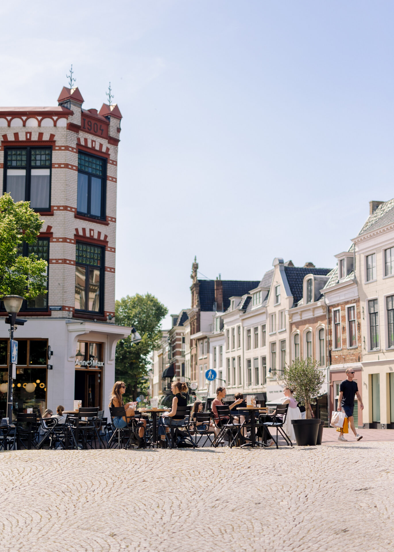 Mensen zitten op het terras aan de Brol, tussen de historische grachtenpanden.