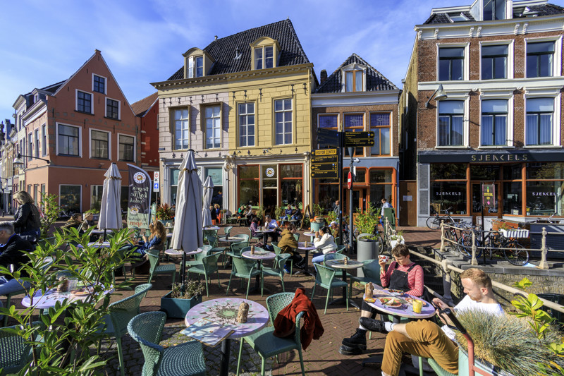 Het terras van bagels en beans o[ een zonnige dag met verdeeld over het terras, een aantal mensen